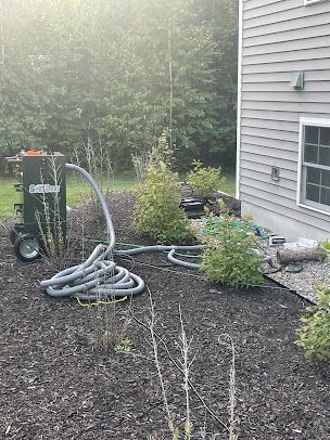 A hose is connected to a machine in the backyard of a house.