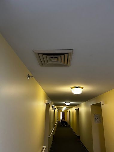 A long hallway with yellow walls and a ceiling fan.