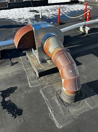 A rusty pipe is sitting on top of a roof.