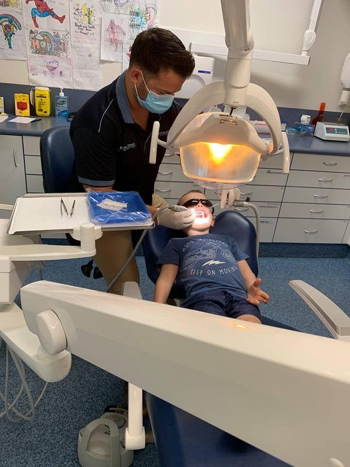 A Dentist Is Examining a Child's Teeth in A Dental Office — Steve King Dental Group in Manunda, QLD
