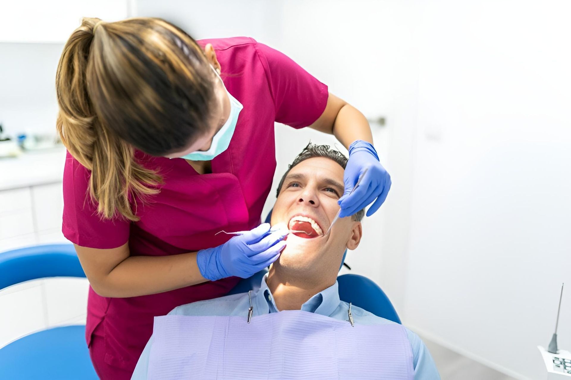 A Woman Is Examining a Man's Teeth in A Dental Office — Steve King Dental Group in Mossman, QLD