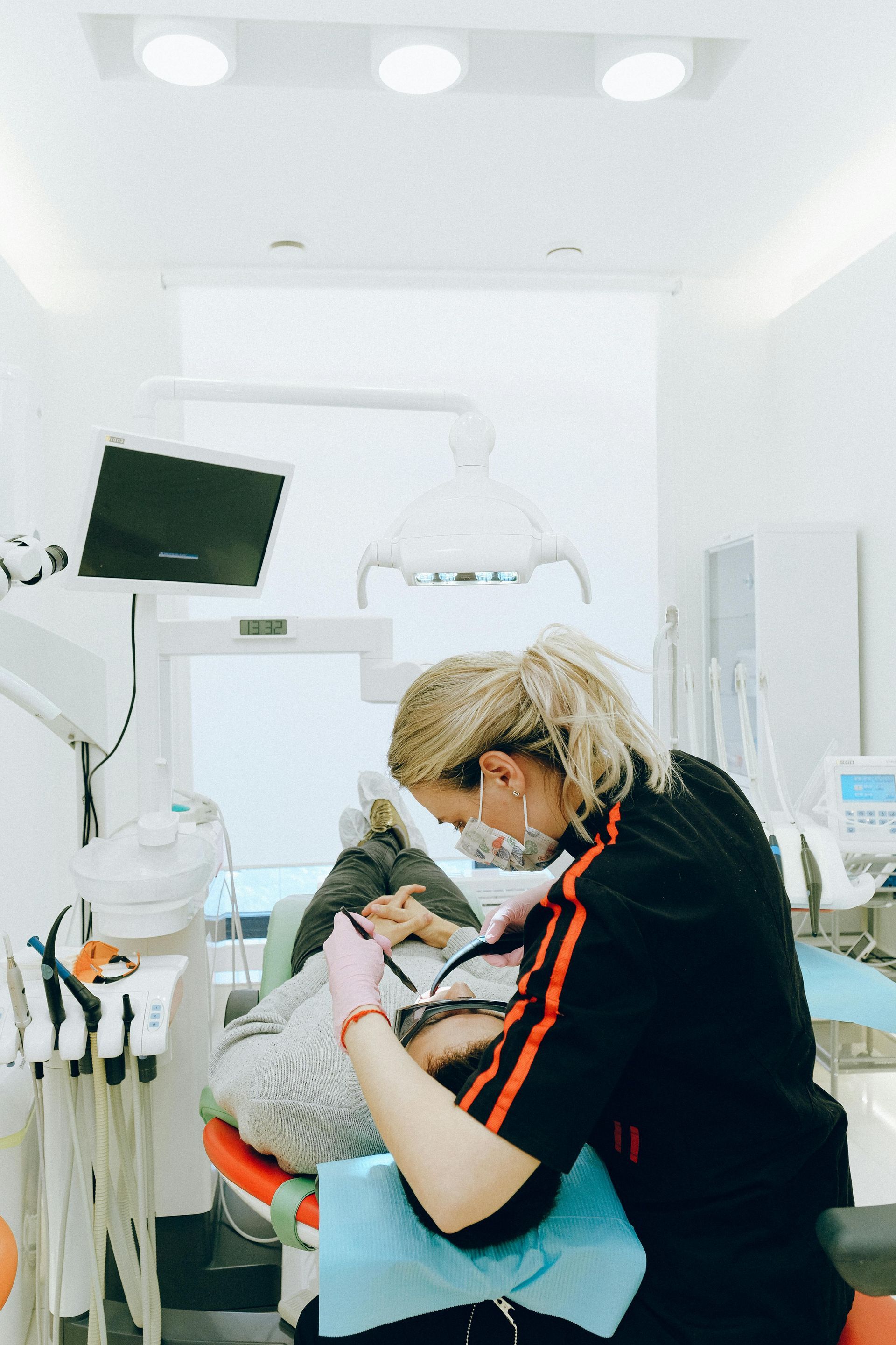 A Female Dentist Is Smiling While a Man Examines a Woman's Teeth in A Dental Office — Steve King Dental Group in Manunda, QLD