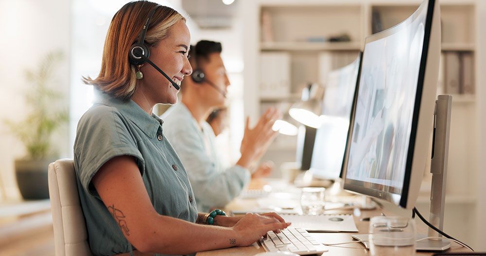 Call center agents wearing headsets working at computers in a bright office