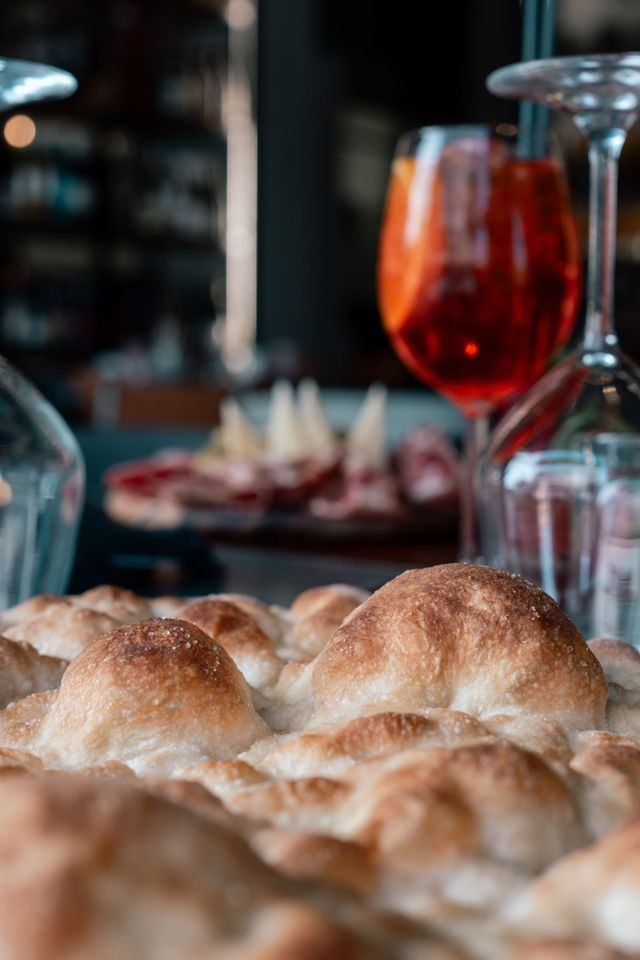 Panini su un tavolo con un bicchiere di bevanda rossa in un ristorante illuminato da luci soffuse.