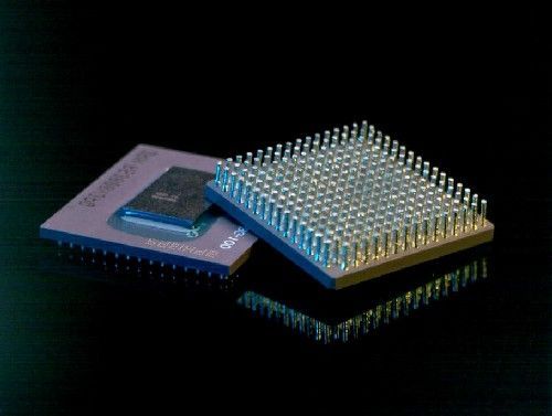 Close-up of two electronic microchips, one with a grid of gold pins on a black background