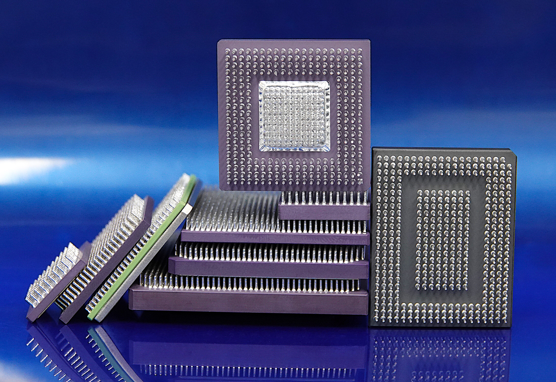 Assorted square computer microchips on a blue background, shown in metallic gray and green