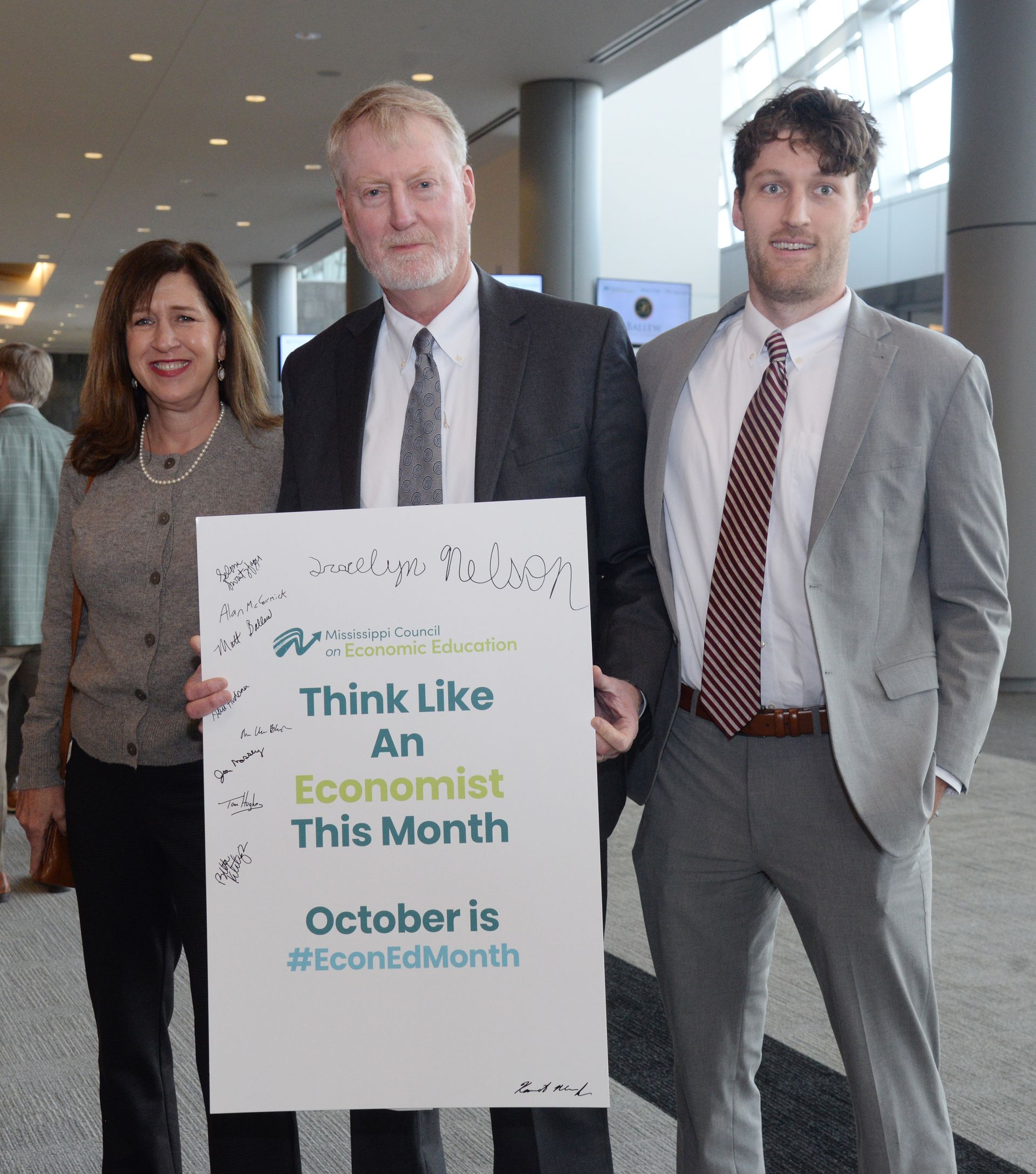 Three people holding a sign that reads 