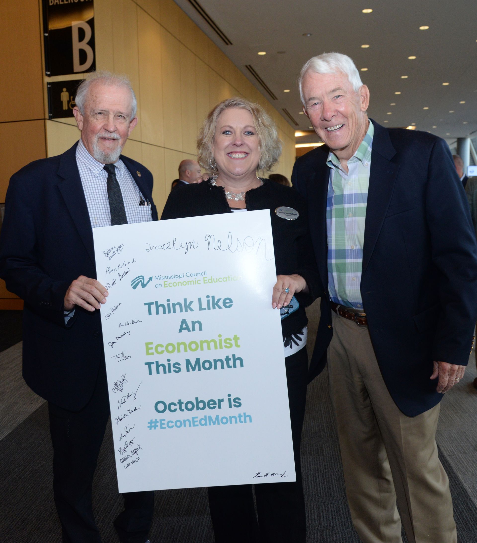 Three people holding a sign that reads 