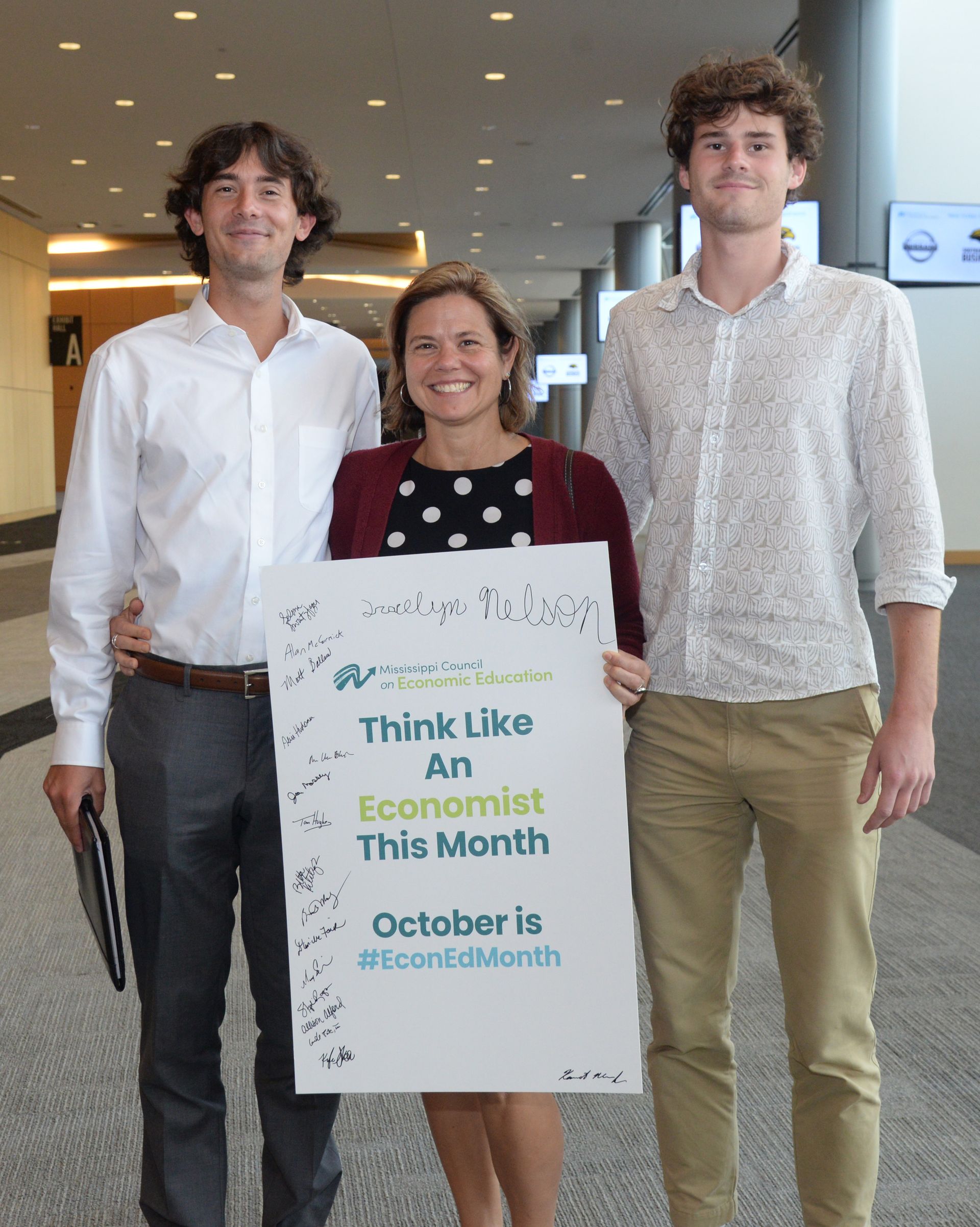Three people hold a sign that reads 