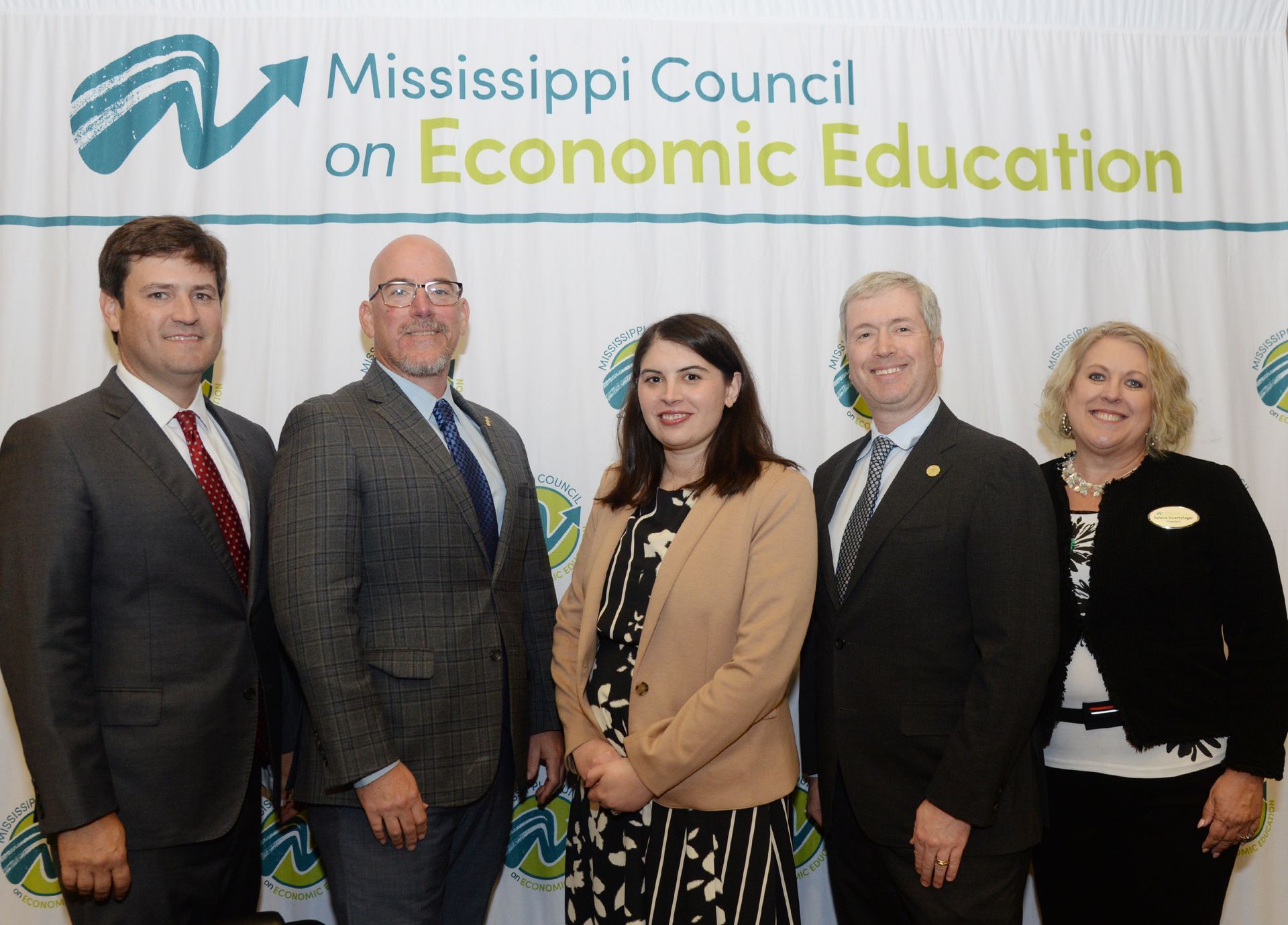 Five people standing in front of a banner for the Mississippi Council on Economic Education.