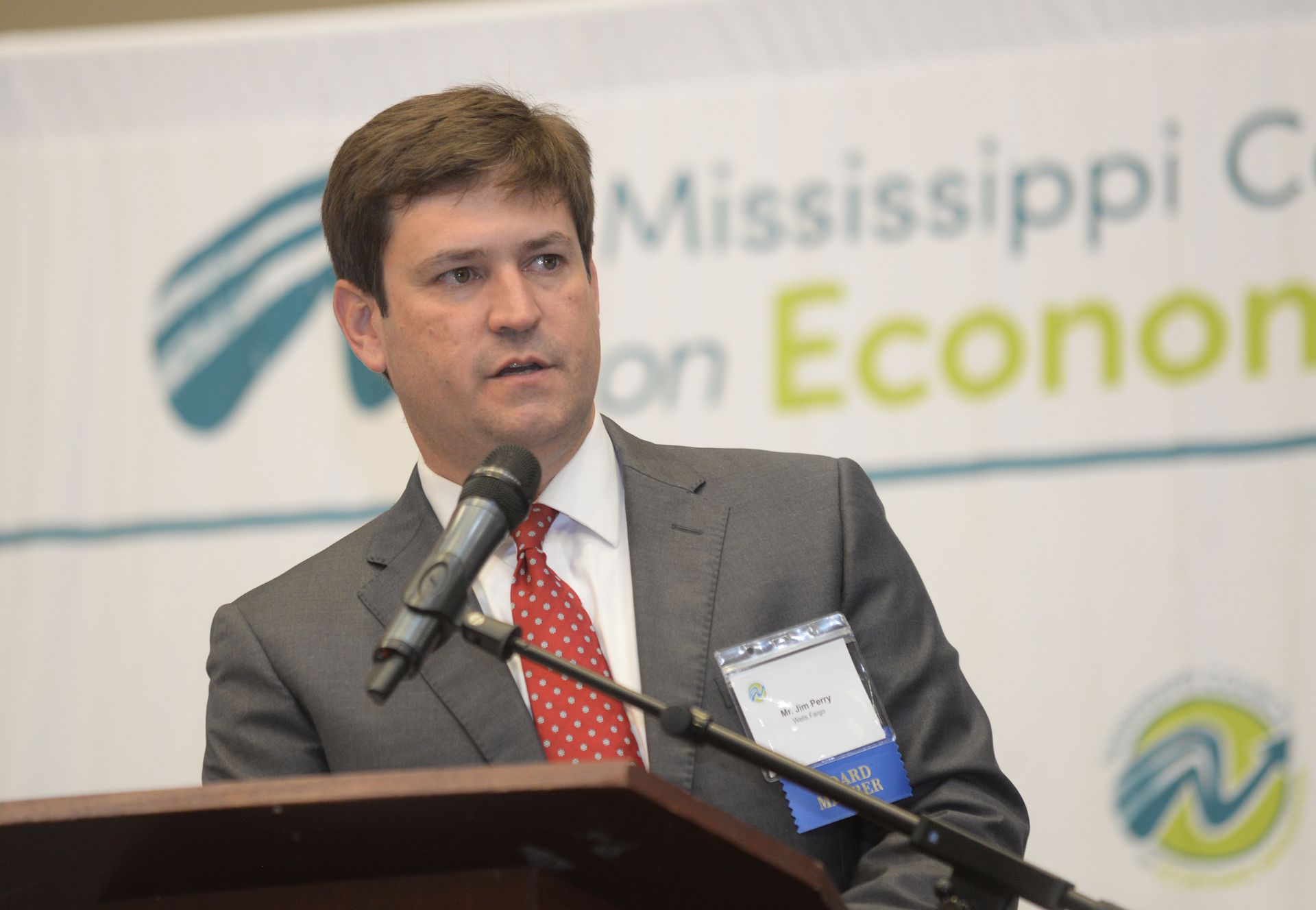 Man in suit speaking at a podium with 