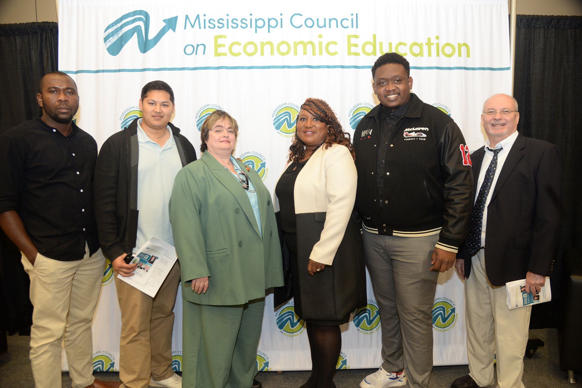 Group of people posing in front of a banner with the logo 