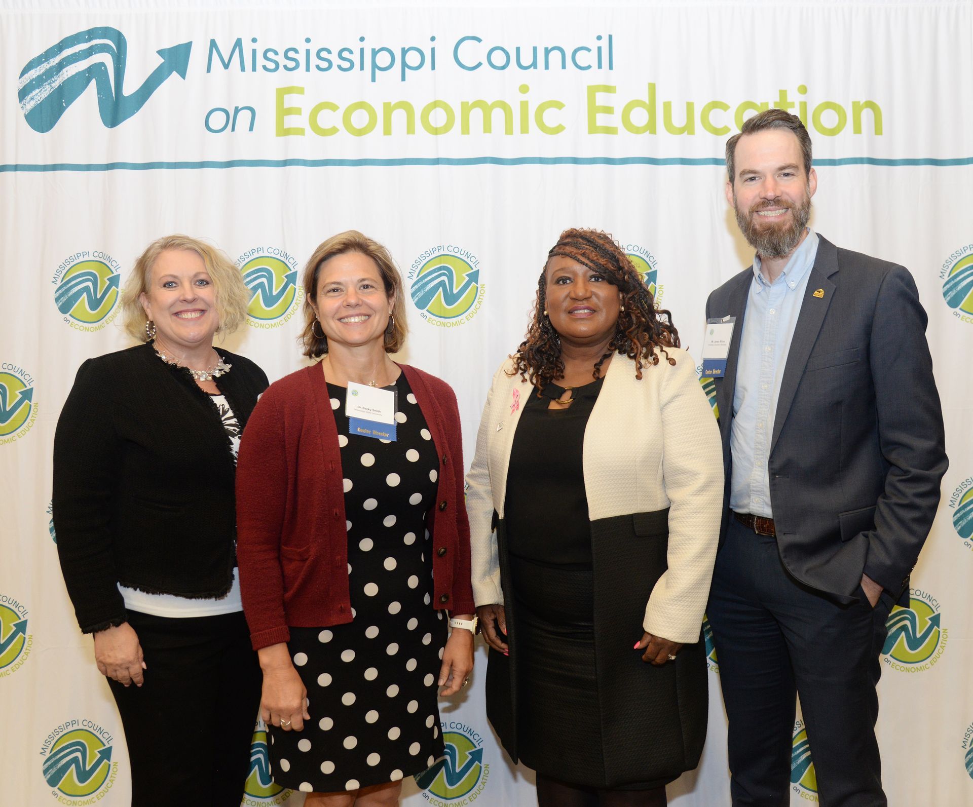 Four people stand in front of a Mississippi Council backdrop.