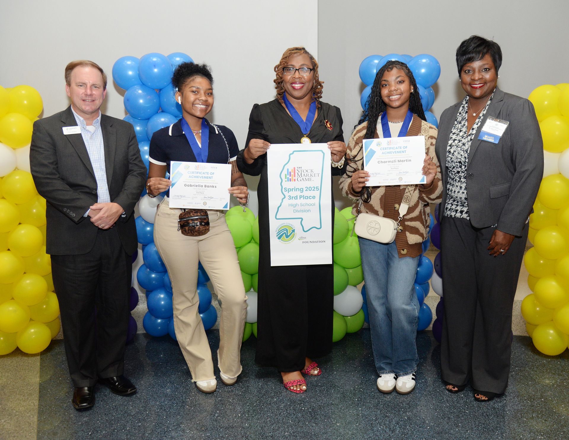 People holding awards and a map of Mississippi pose with balloons.