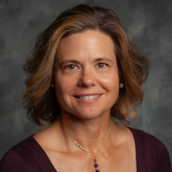 A woman with short hair and hoop earrings is smiling for the camera.