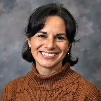 A woman in a suit and blue shirt is smiling for the camera.
