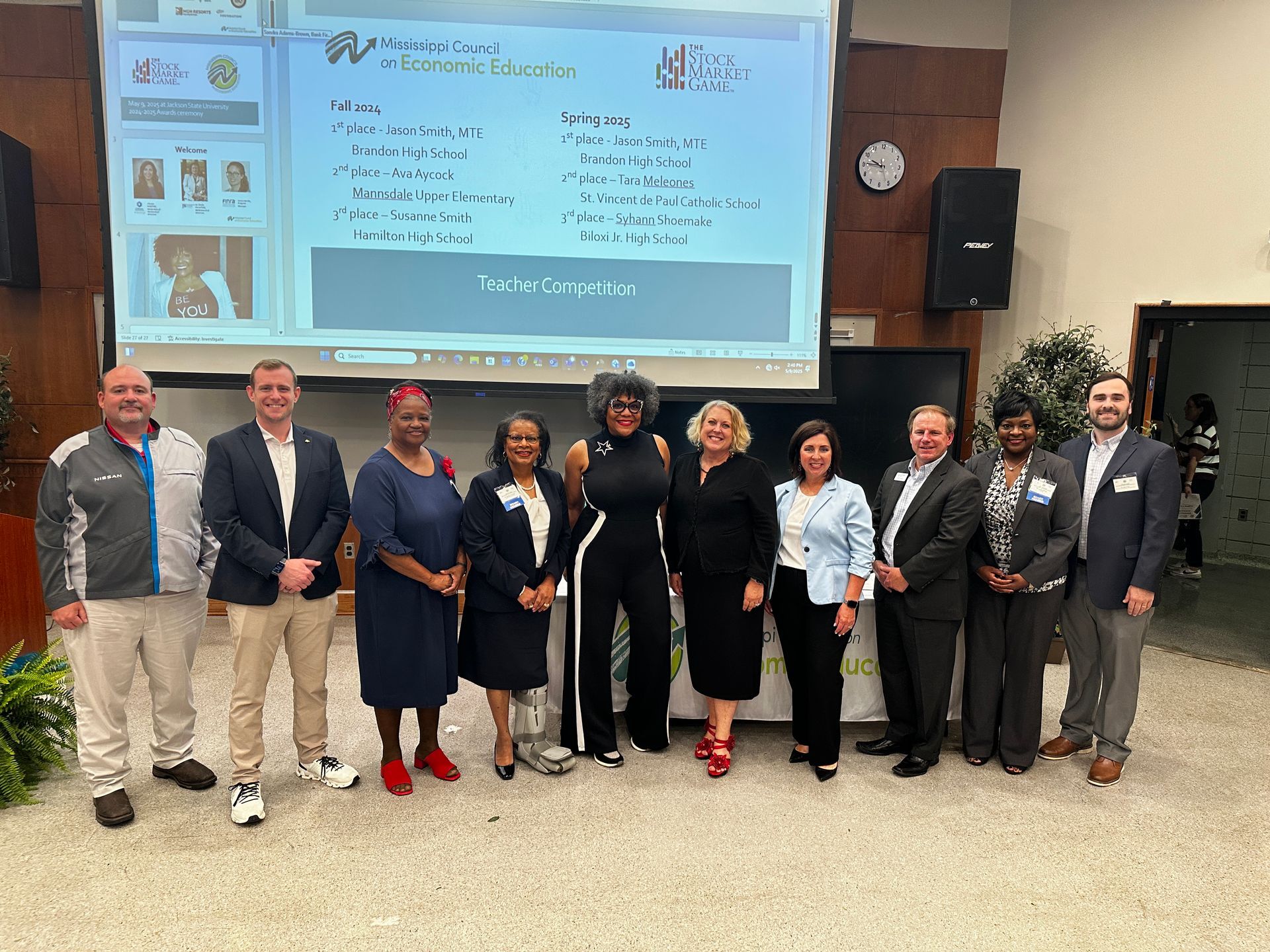 Group of people standing in front of a screen at an event.