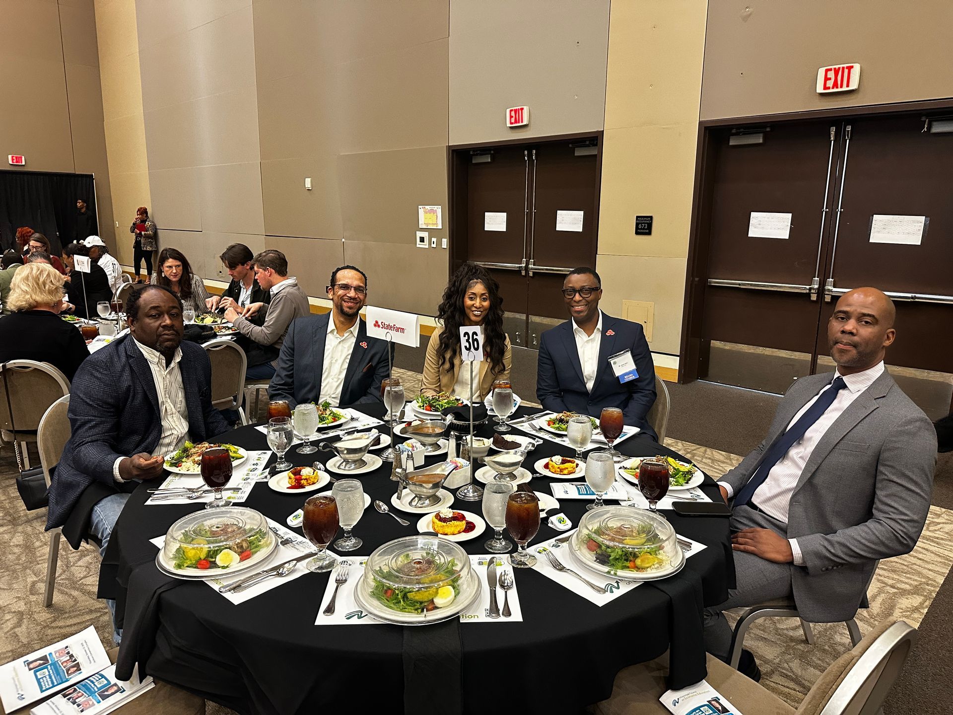 People at a round table, a banquet hall. Some have food in front of them.
