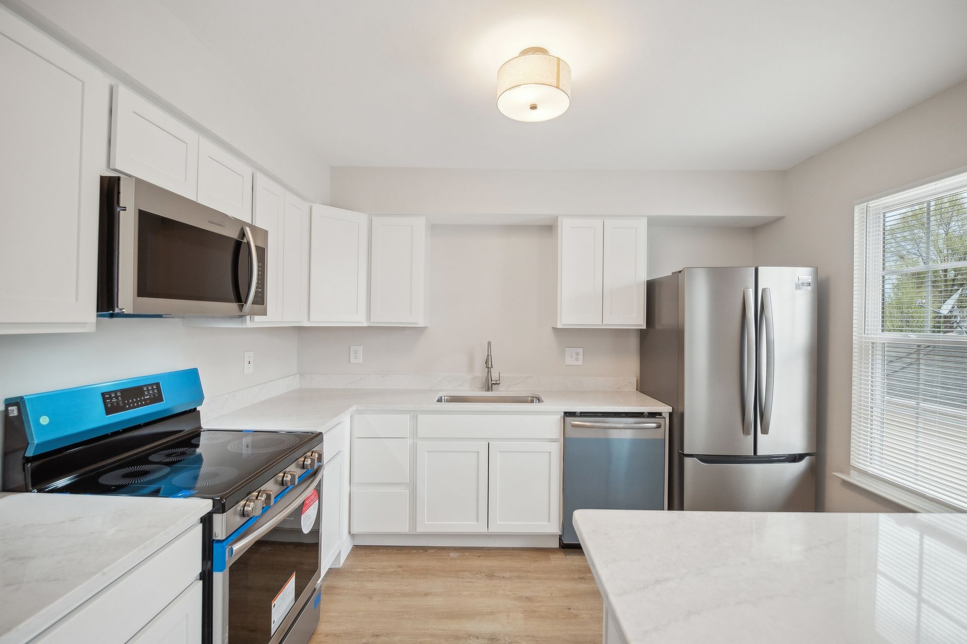Bright modern kitchen with white cabinets, stainless appliances, and a blue stove