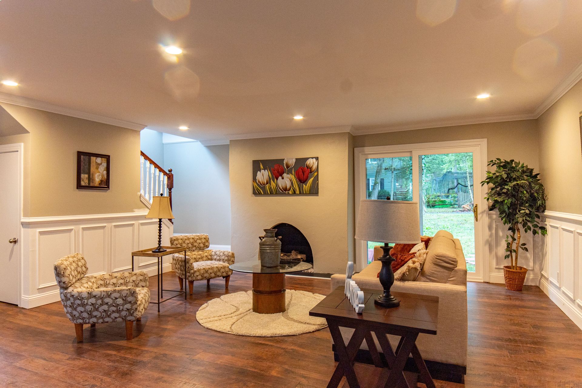Spacious living room with beige furniture, fireplace, bay window, and warm recessed lighting.