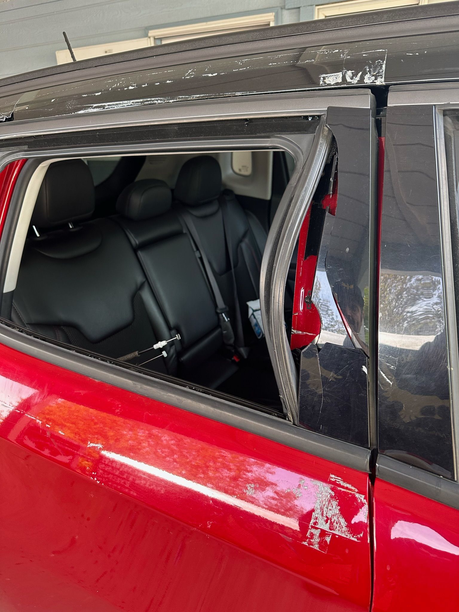A red car with a broken window is parked in a garage.
