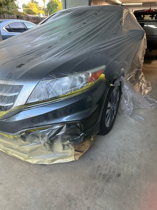 a black car is covered in plastic and yellow tape