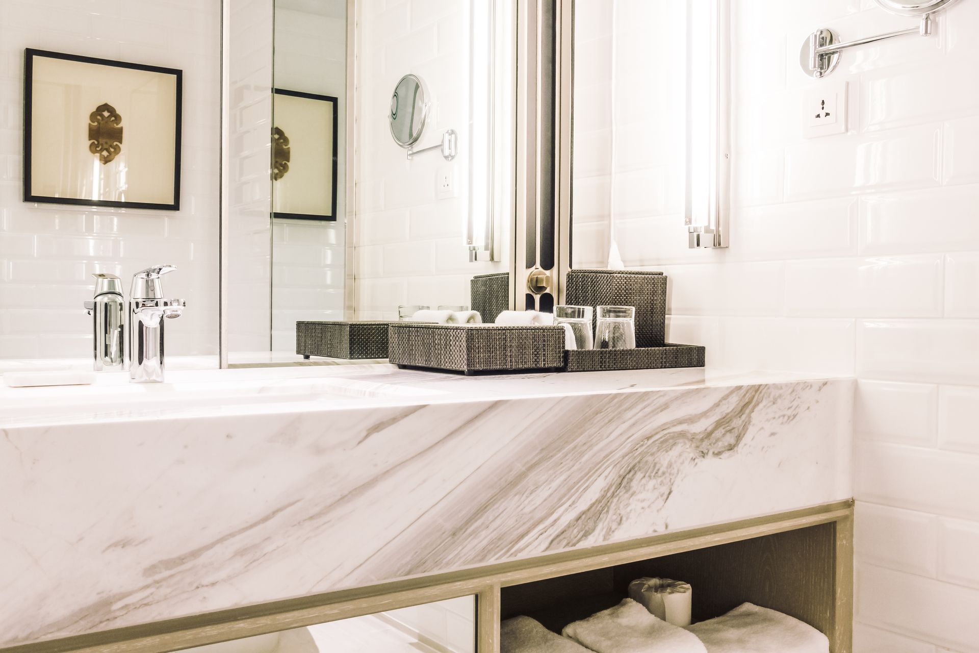Bright modern bathroom vanity with marble sink, mirror, and neatly folded towels.