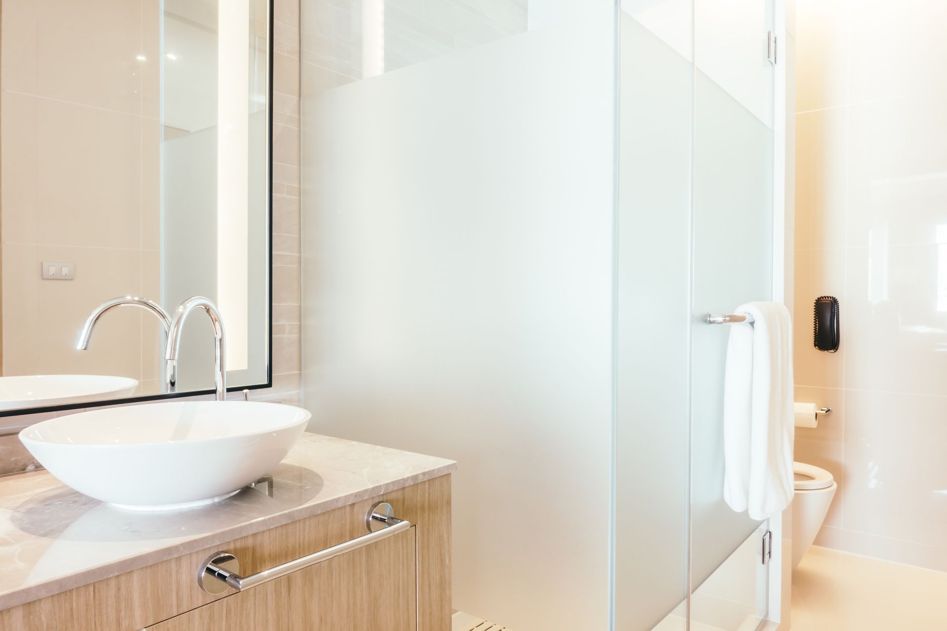 Modern bathroom with vessel sink, mirror, frosted glass shower, and toilet
