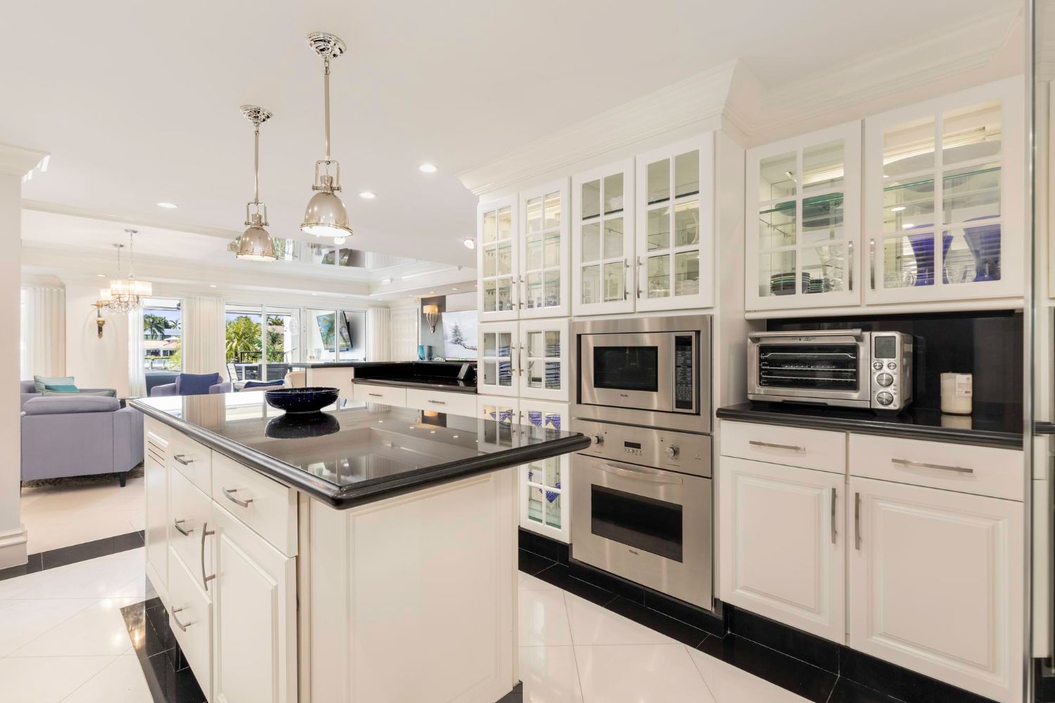 Bright modern kitchen with white cabinets, black countertops, island, and built-in stainless-steel appliances