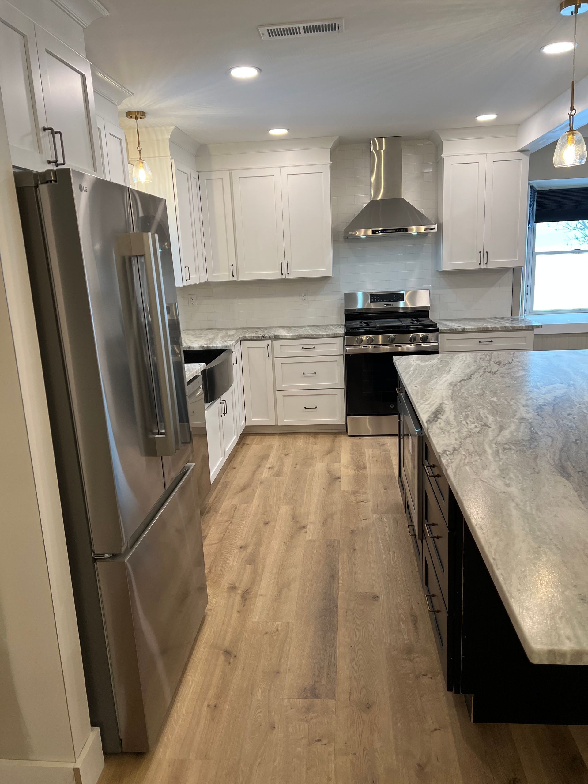Modern kitchen with stainless steel appliances, white cabinets, and a granite island.