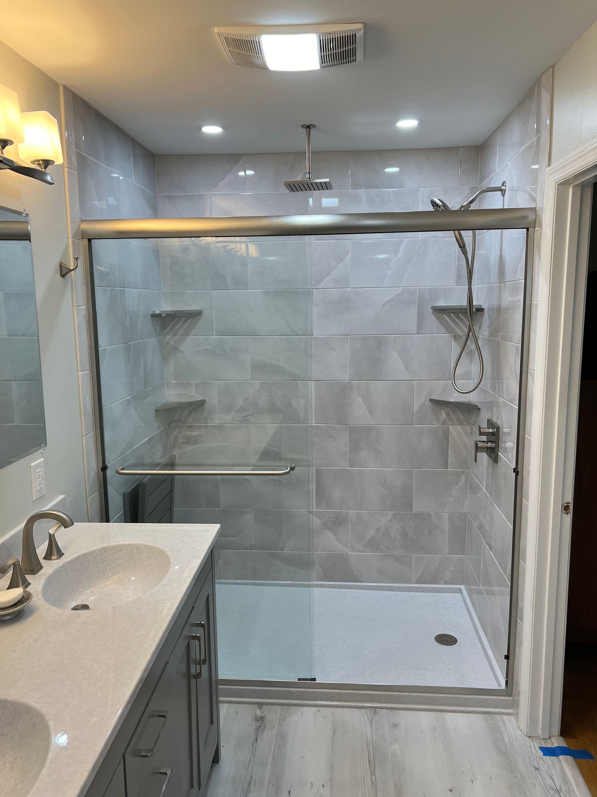 A bathroom with a sliding glass shower door and two sinks.