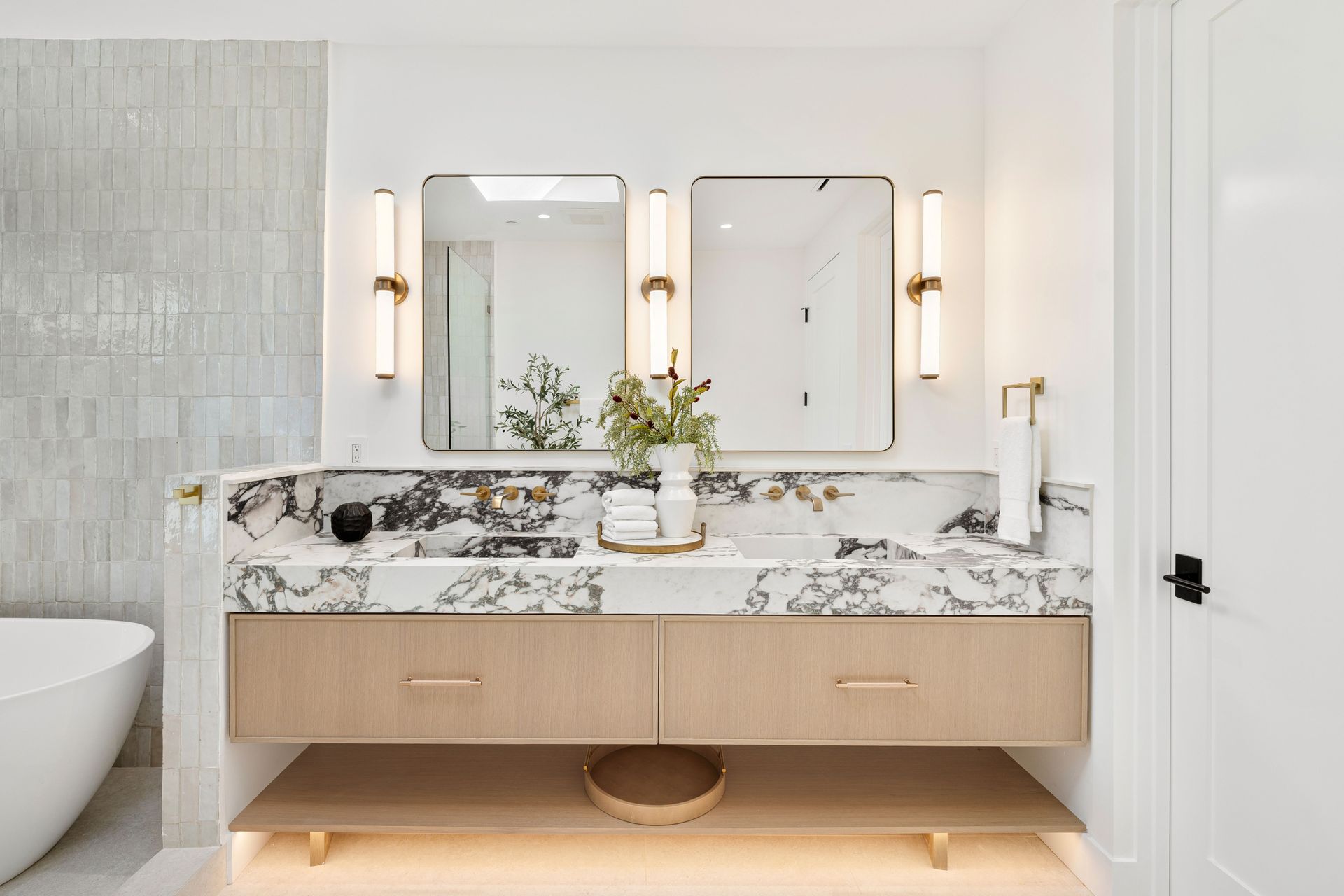 A bathroom with two sinks , a mirror and a bathtub.