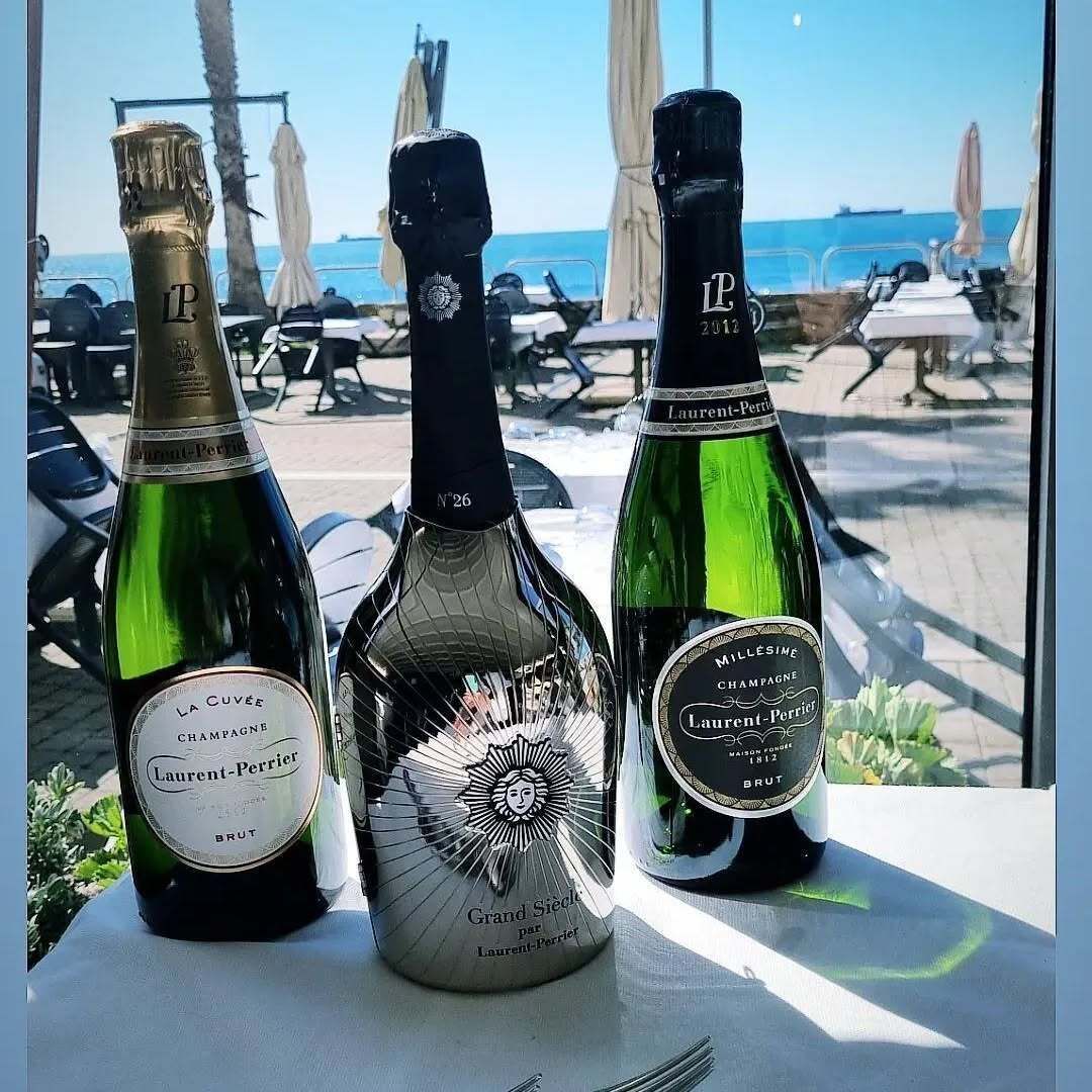 Tre bottiglie di champagne sono appoggiate su un tavolo davanti a una finestra