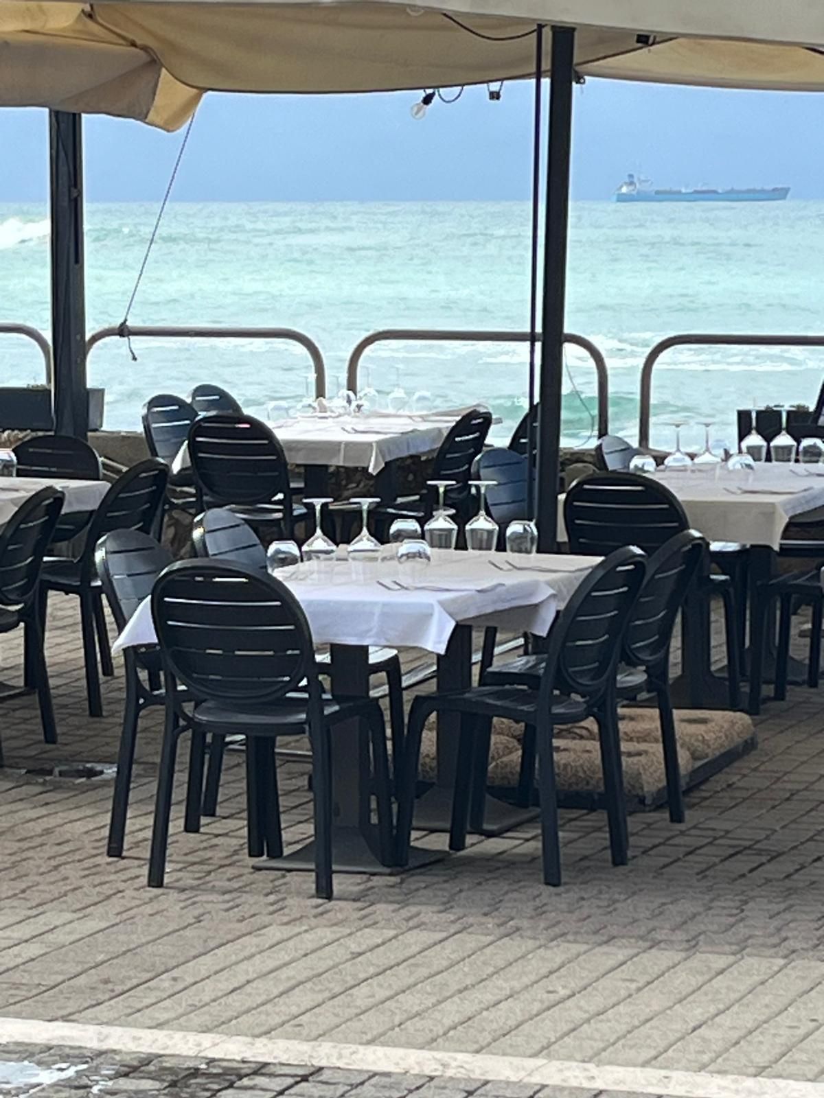 Un ristorante con tavoli e sedie di fronte all'oceano