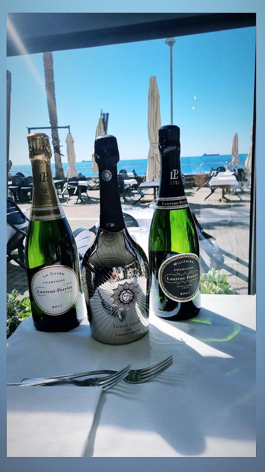 Tre bottiglie di champagne sono appoggiate su un tavolo davanti a una finestra.