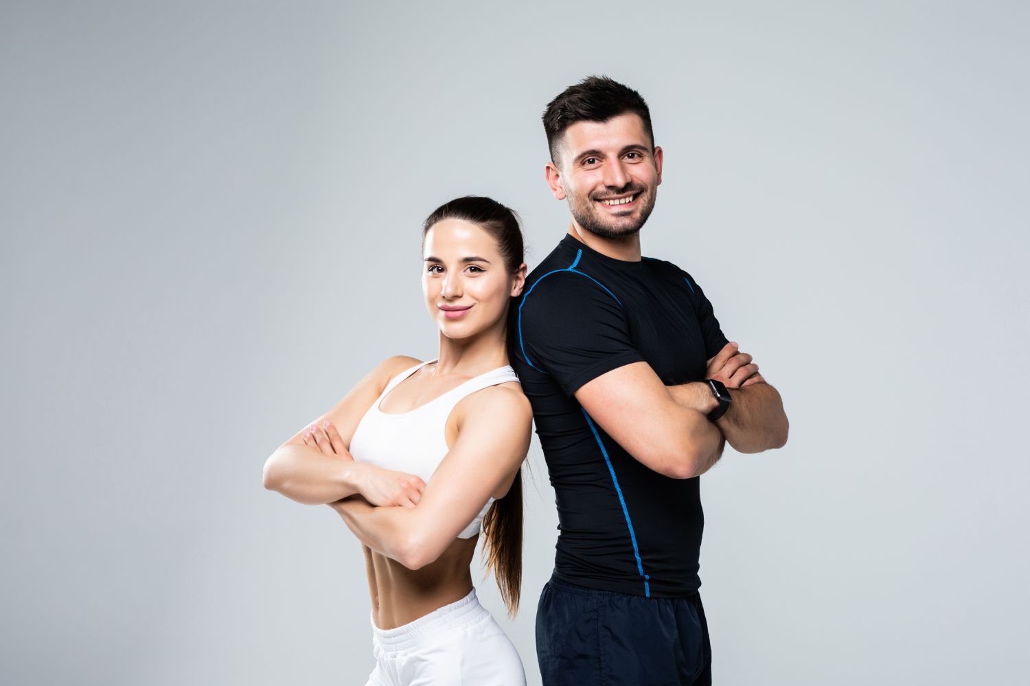 A man and a woman are standing back to back with their arms crossed.