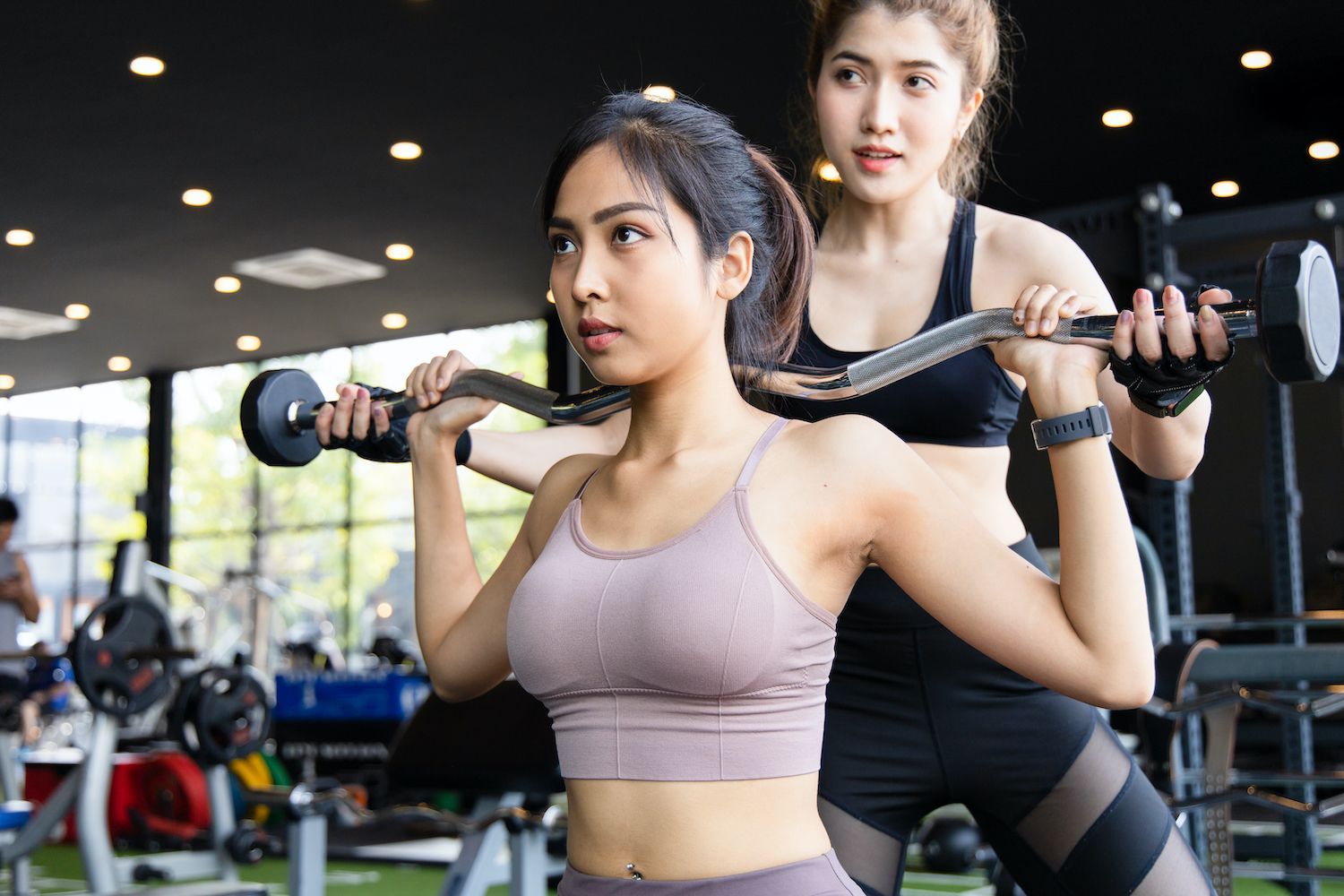 Two women are lifting dumbbells in a gym.