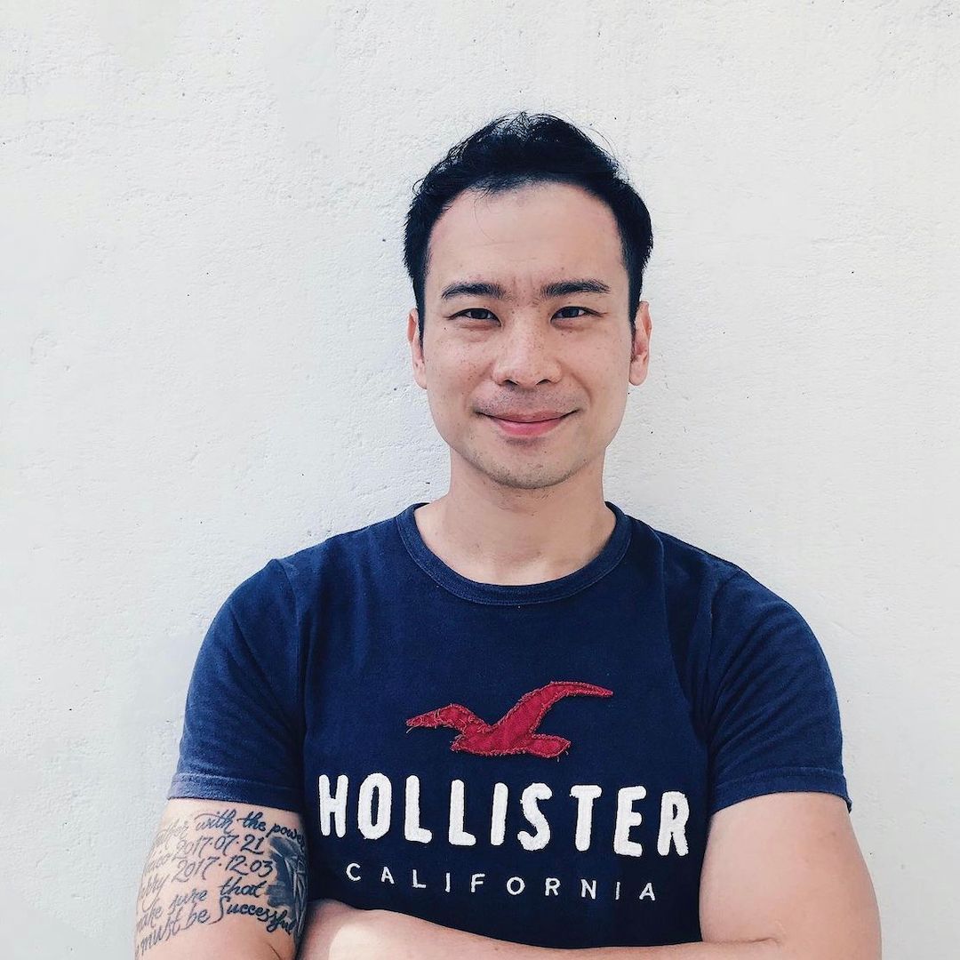 A man wearing a hollister california t-shirt with his arms crossed