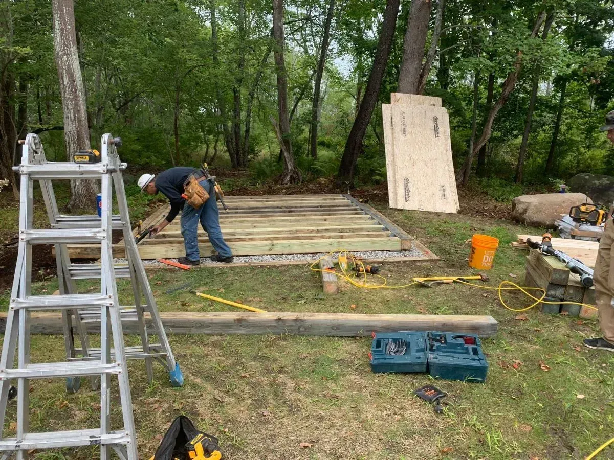 A man is working on a wooden structure in the woods.