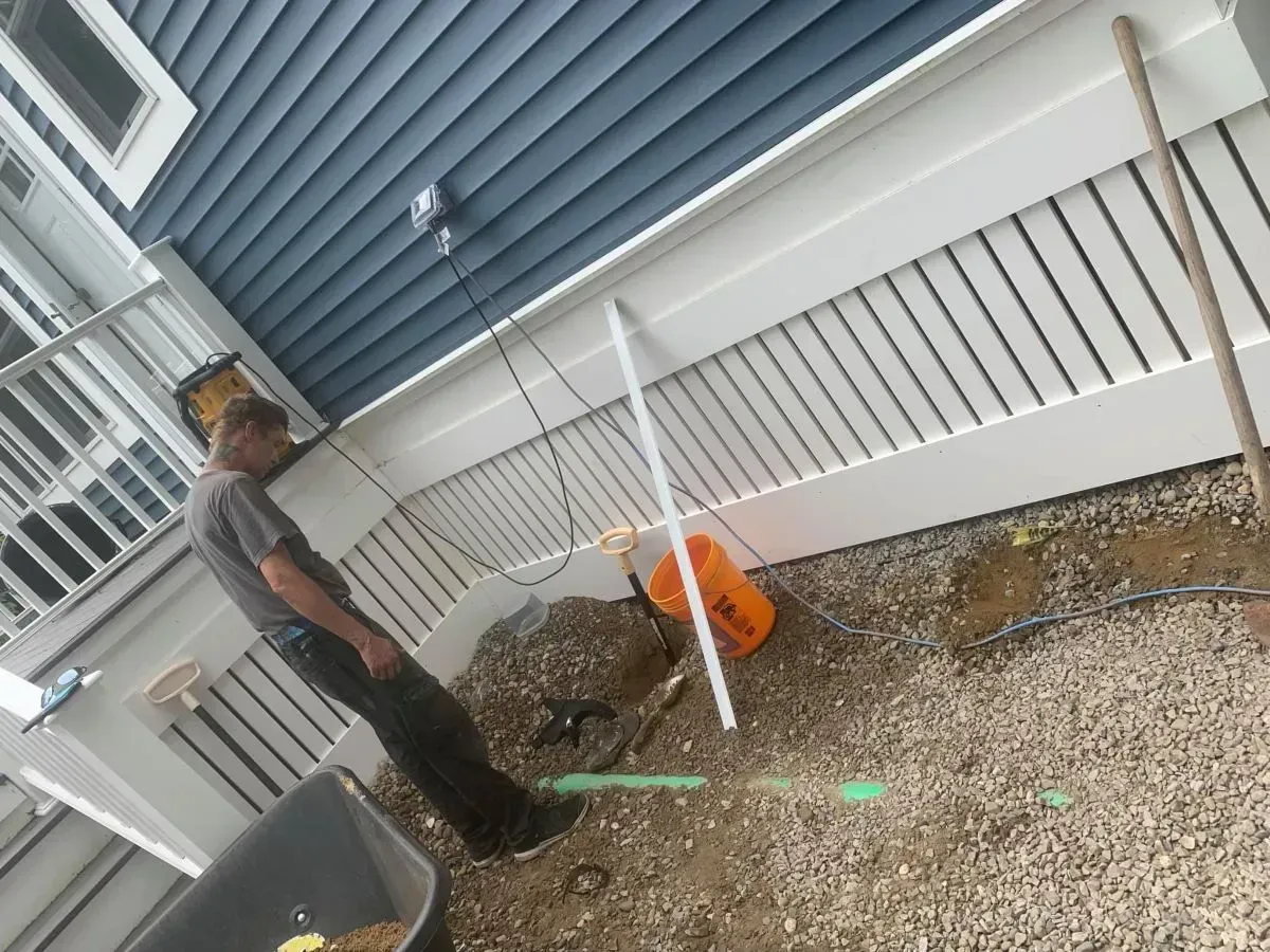 A man is standing next to a wheelbarrow in front of a house