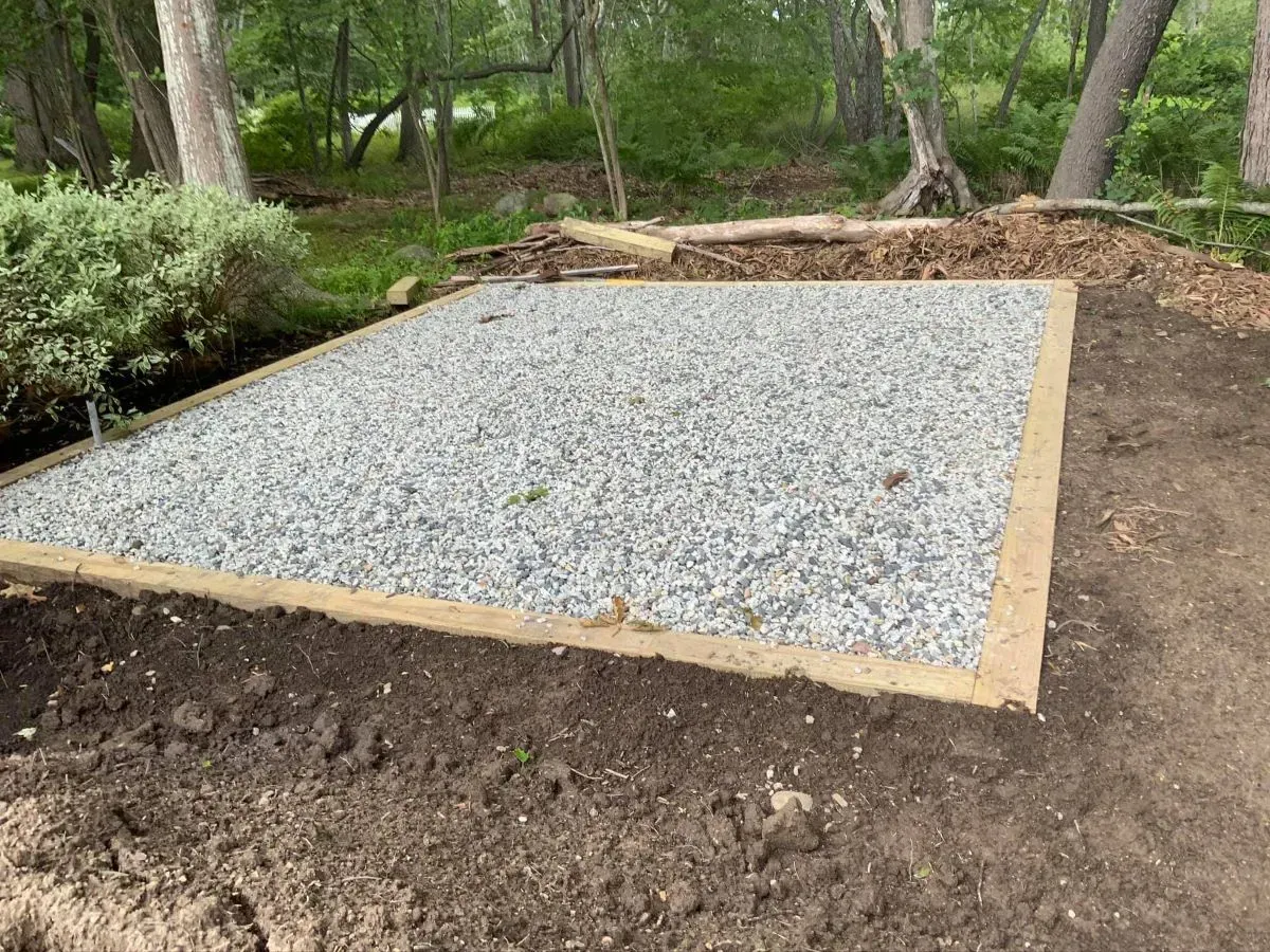 A pile of gravel is sitting on top of a pile of dirt in the middle of a forest.