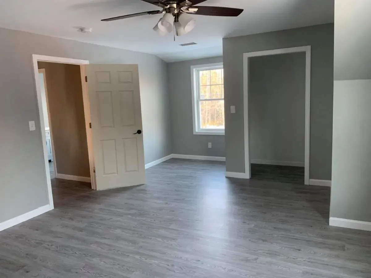 An empty room with a ceiling fan and a window