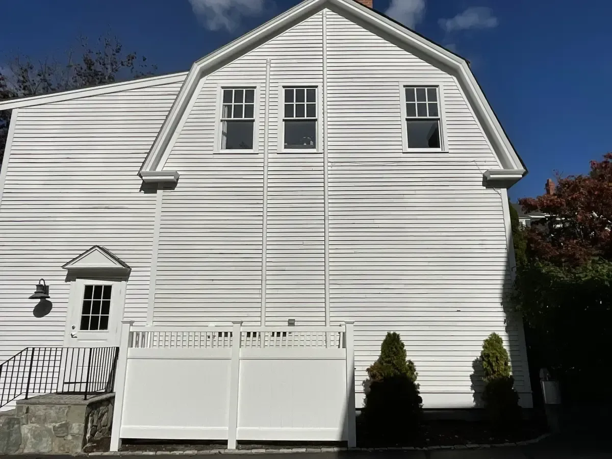 A white house with a white garage door and a blue sky in the background.