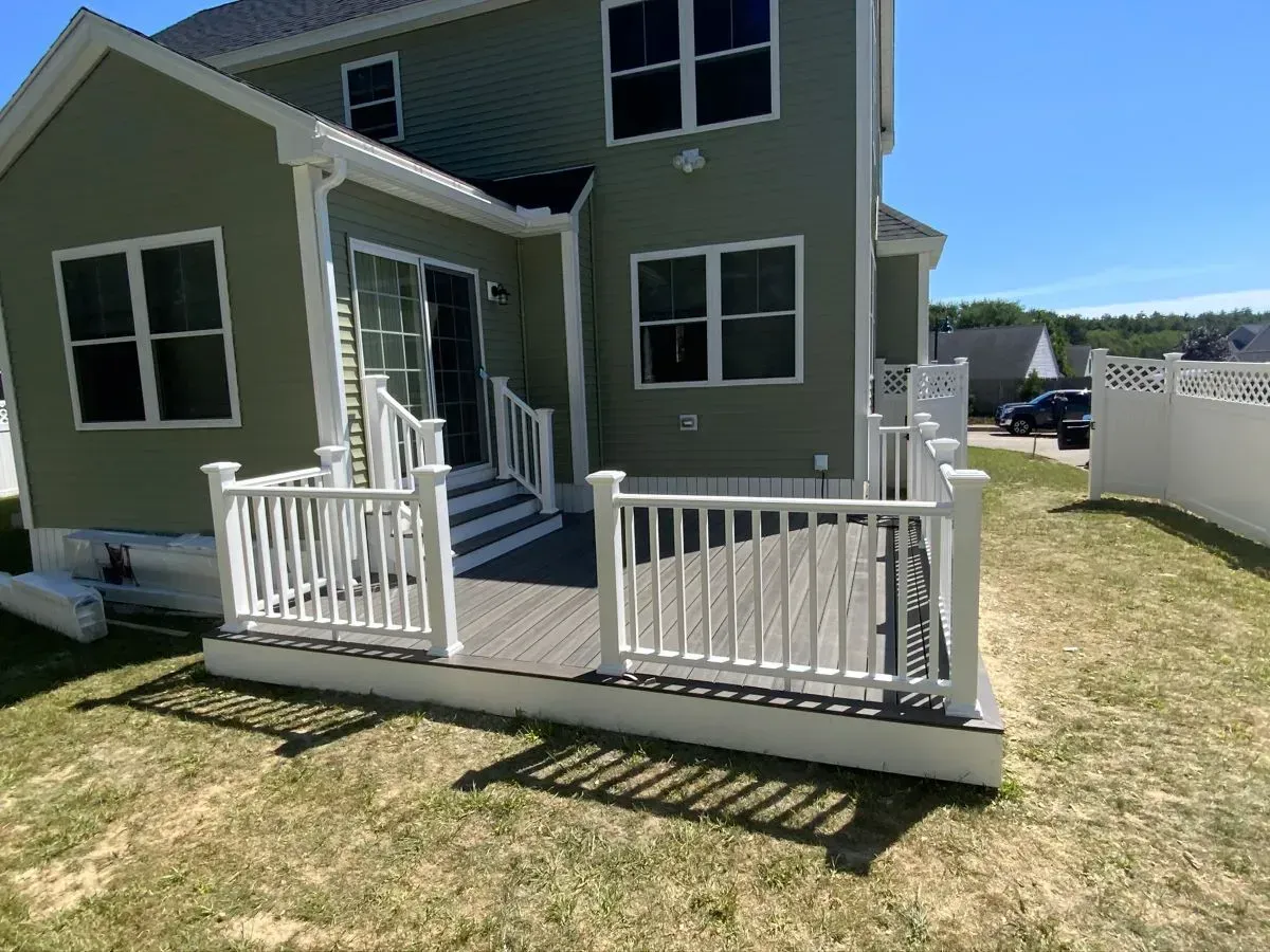 A house with a deck and a white railing in front of it.