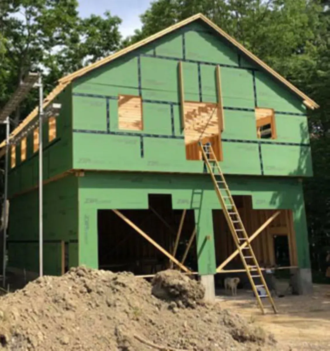 A green building under construction with a ladder in front of it