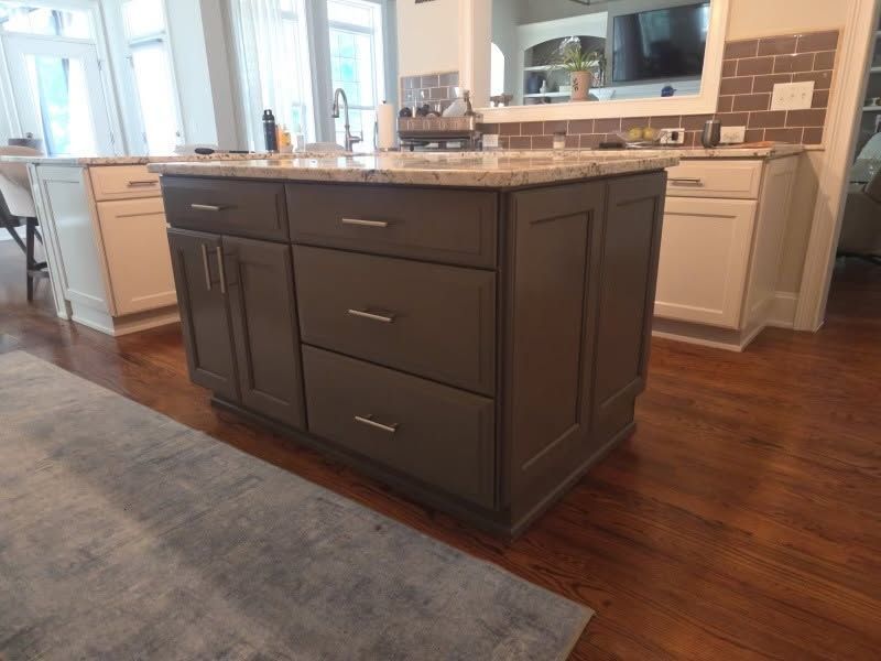 Dark kitchen island with drawers and cabinet doors in a bright modern kitchen