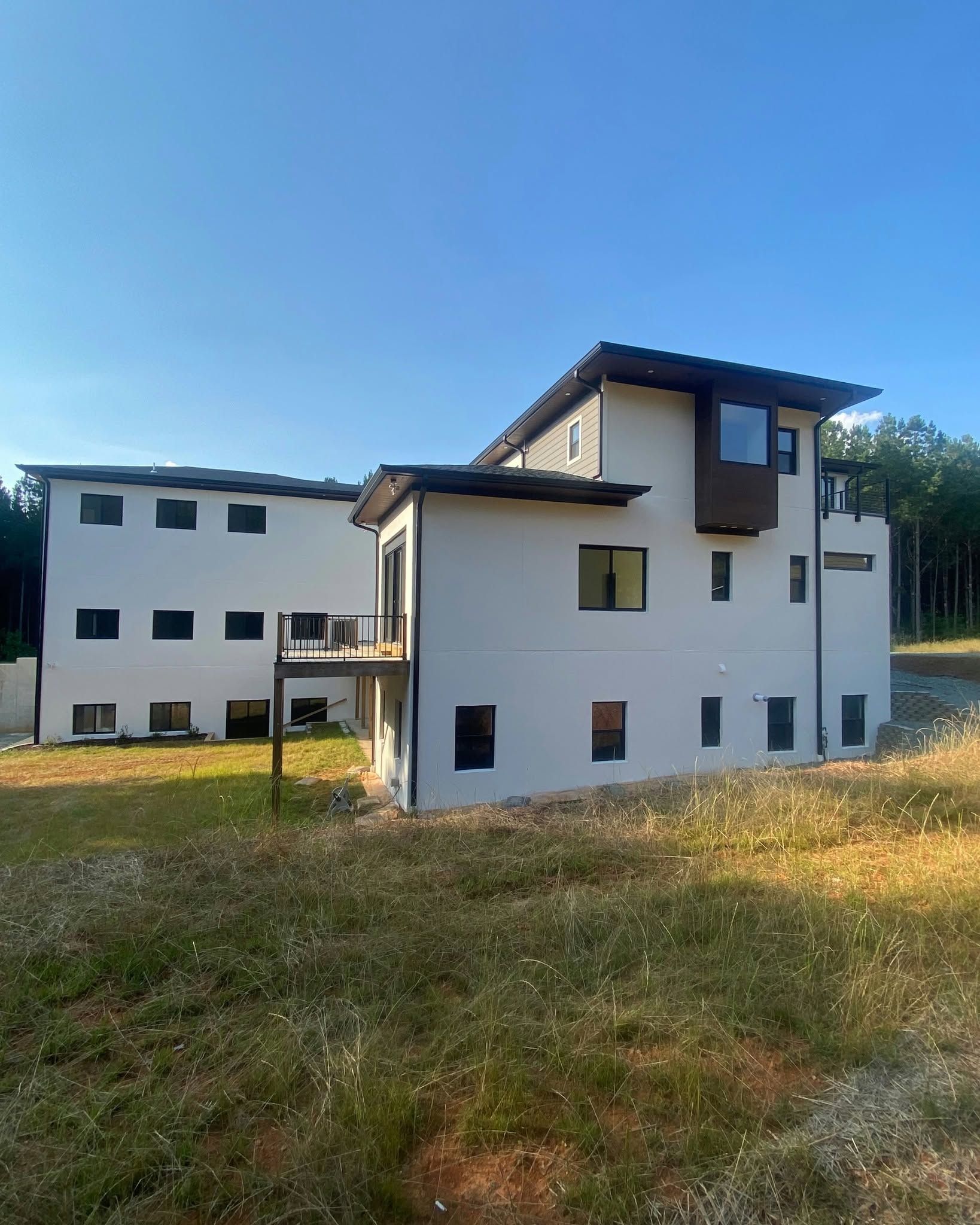 Modern white apartment buildings in a grassy field under a clear blue sky