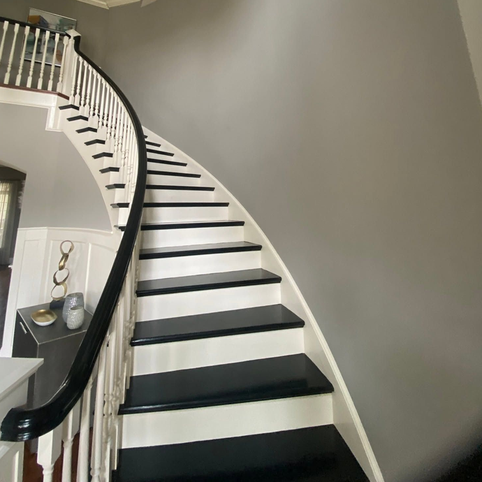 Curved staircase with black-and-white steps and a black handrail in a modern interior.