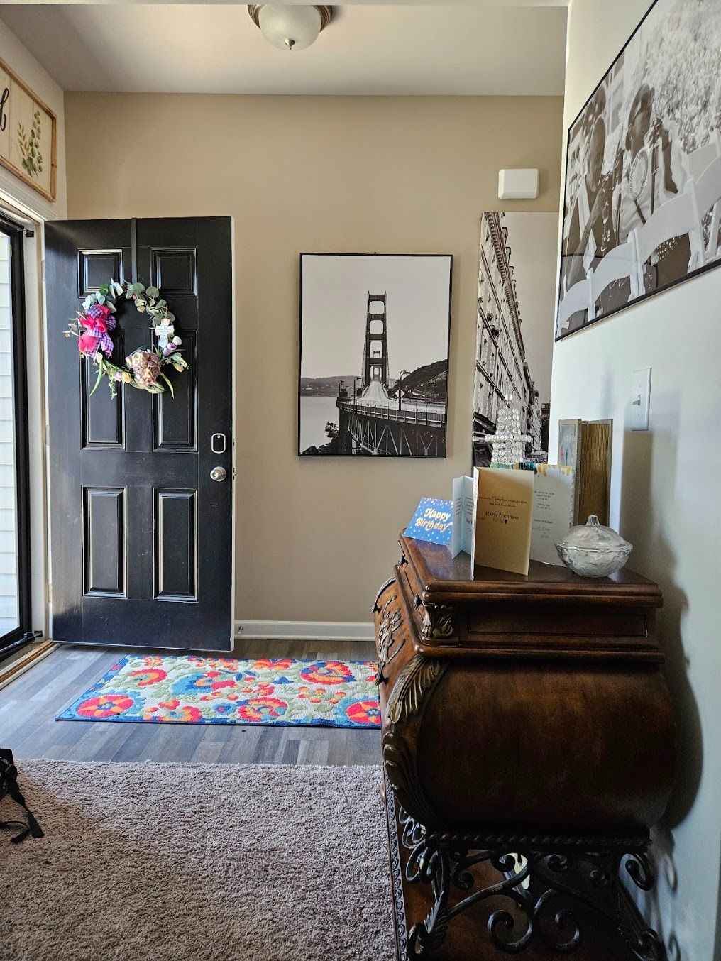 Entryway with black door, colorful rug, Eiffel Tower art, and carved wooden chest.