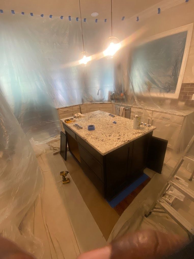 Kitchen under plastic sheeting with a granite island and cabinets, mid-renovation